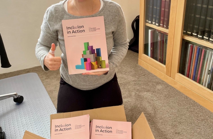 Iva Strnadova sits with her new book, Inclusion in Action, and gives a thumbs up