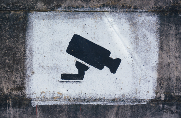 The image of a CCTV camera spray painted on a white concrete background