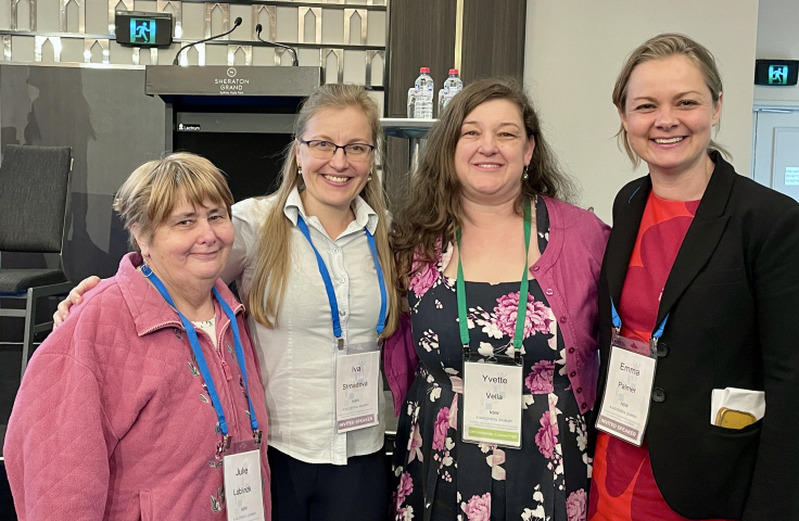 Four women are standing together and smiling for the camera