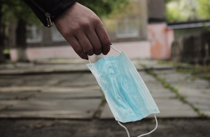 A person holding a surgical mask outside