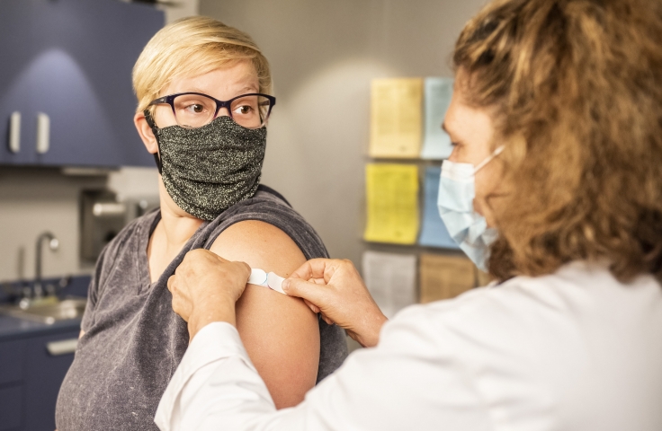 A woman wearing a mask being vaccinated