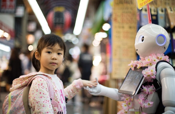 Young girl holds hands with a robot