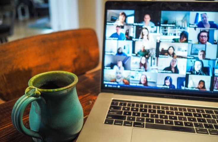 A laptop showing an online meeting, with a green mug to the side