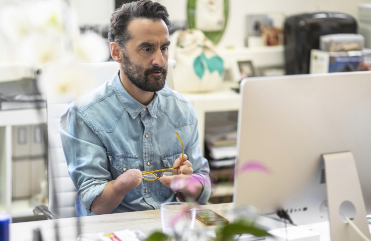 Man with amputated hand working at a computer