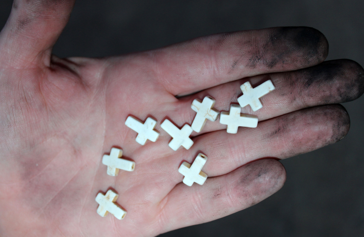 A person holding 8 small white crosses in the palm of their hand