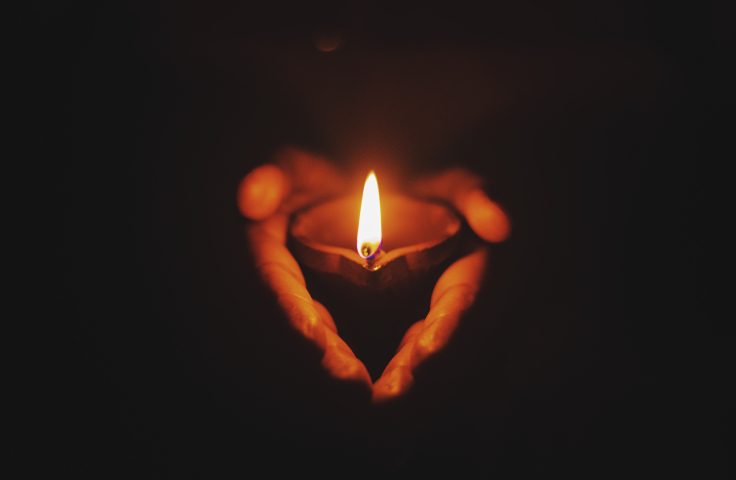 Hands holding a lit candle