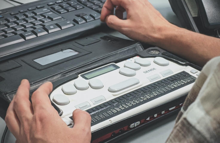 Blind man using a braille screen reader.